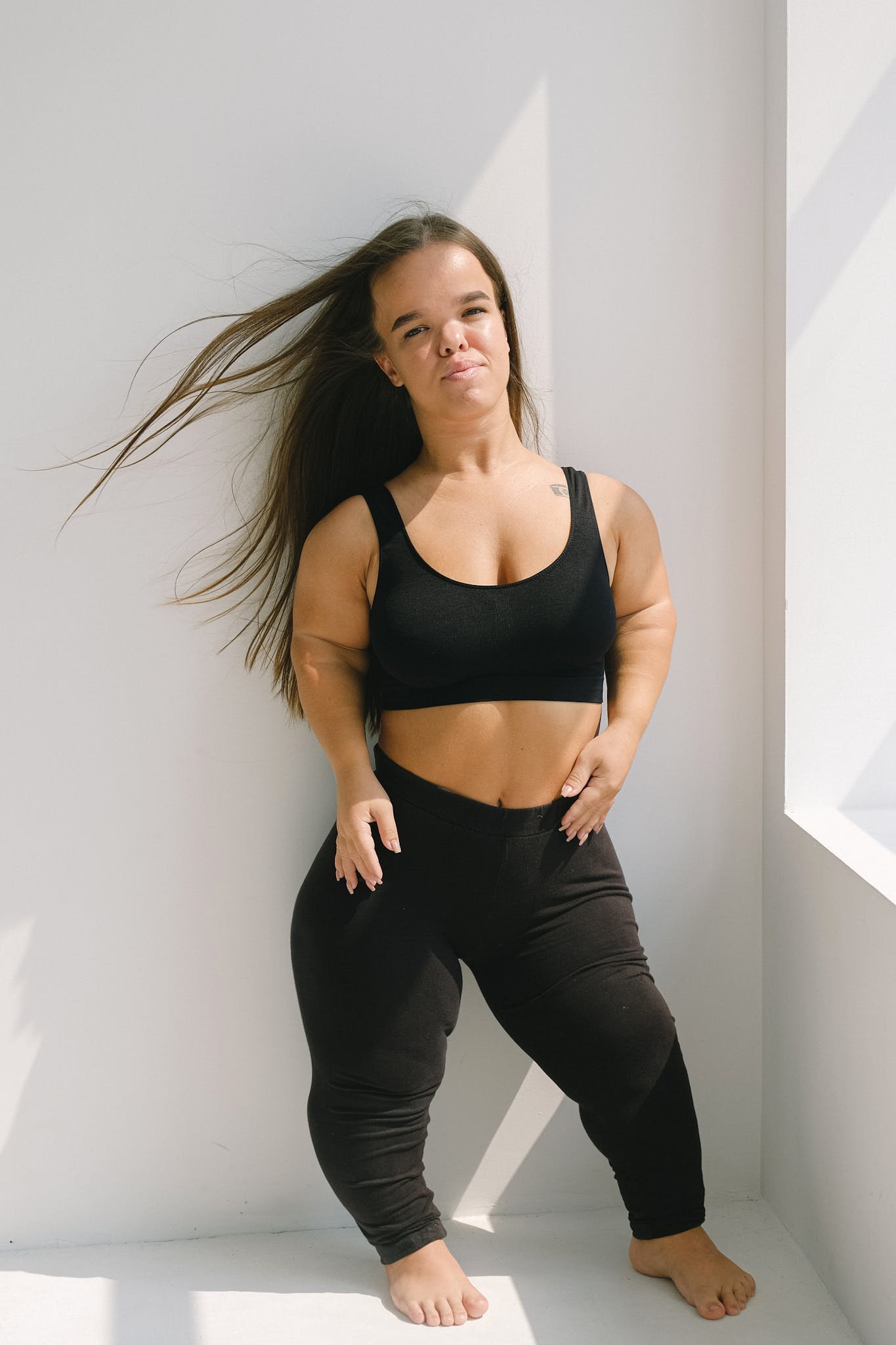 A strong and confident woman posing in activewear, embracing her uniqueness and beauty.