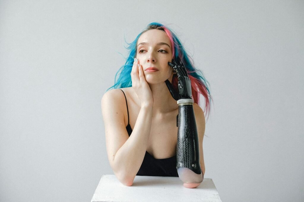 Creative portrait of a young woman with a prosthetic arm and vibrant colored hair.